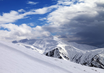 Fototapeta na wymiar Ski slope in evening and storm clouds