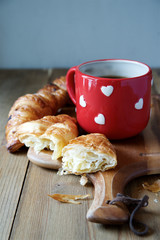 Romantic breakfast with croissants and coffee in cup with hearts 
