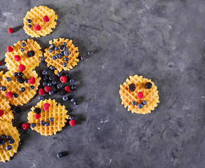 Belgian waffles with berries on the gray background. Sweet food concept. Copyspace. Fresh berries, raspberries, blueberries, blackberries. waffle with smile face. Funny waffle. Top view, flat lay
