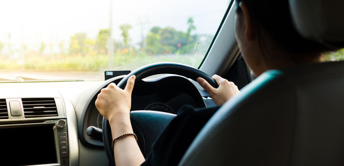 Women driving car on day time, Take photo from inside focus on driver hand