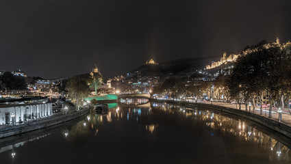 Georgia, Tbilisi - November 23, 2016. The lights of the city at night and reflection in the Kura River, Assumption Church Metekhi, Narikala fortress and the movement of vehicles on the street