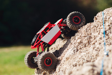 Side view on crawler rising on rock hill. Small buggy car overcoming mountain rough rock. Going to...
