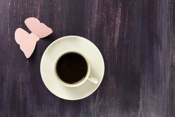 Black coffee and paper butterfly on purple background