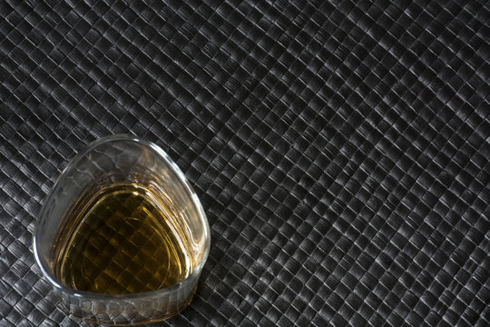 Glass of whiskey on black leather background