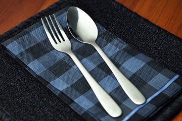 Fork spoon on napkin on wooden table.