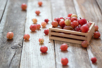 Heap of ripe pink gooseberries on wooden table. Selective focus