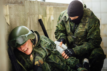 The soldier bandaging his friend in a combat situation.