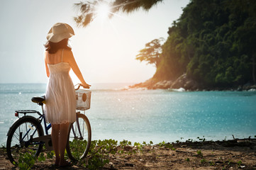 Charming woman in white dress walking bicycle enjoying blue sea and sunray
Holiday in tropical ,woman with sun hat relaxing and happy