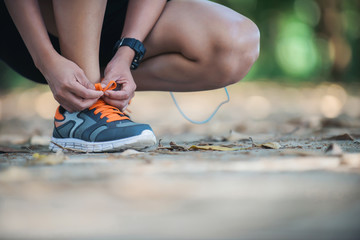 Young fitness woman sitting tie their shoes before she go joggin
