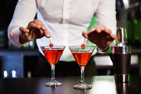 Bartender garnishing cocktail with cherry