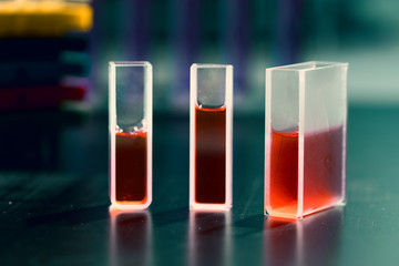 Quartz cuvette for laser chromatography with red liquid. Physical chemistry laboratory