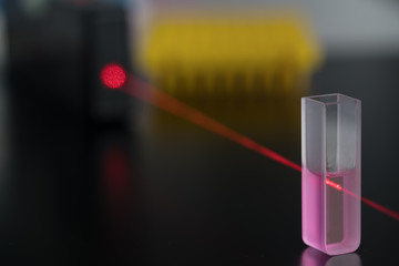 Quartz cuvette for laser chromatography with red liquid. Physical chemistry laboratory