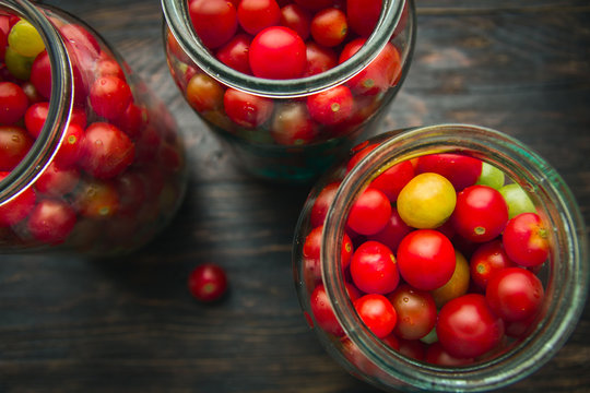 cherry tomatoes in a glass jar on a wooden background
