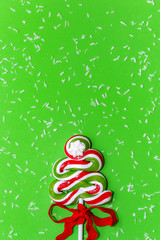 Candy Christmas tree and snowfall on green background. Let it sn