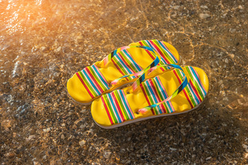 Flip flops on a shore. Sunlight and transparent water. Be closer to the sea. Spend vacation at exotic island.