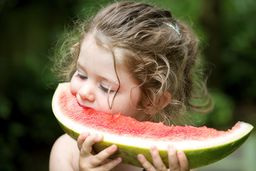Portrait of cute little girl eating a slice of watermelon