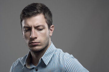 Dramatic intense high contrast portrait of upset young businessman looking back over the shoulder