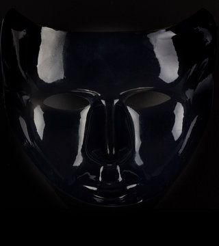 Shiny black mask silhouette on pitch black background.