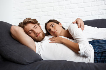 Young beautiful couple relaxing resting lying on sofa at home.