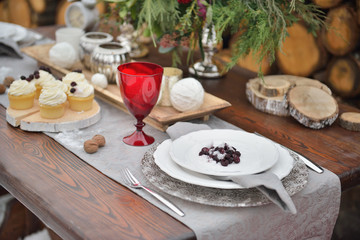 Obraz na płótnie Canvas Decorated Christmas holiday table ready for dinner. Beautifully set with candles, spruce twigs, plates and serviettes wedding event outdoor
