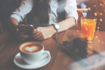 Woman holding mobile phone in hands, reading news from the internet, breakfast of handsome business lady