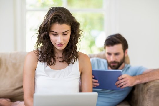 Young couple using digital tablet and laptop