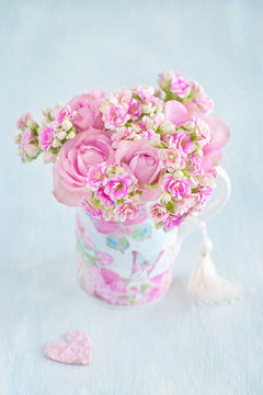 Lovely bunch of a pink flowers in a vase ,decorated with a heart on a table .Vintage style ,grunge paper background.