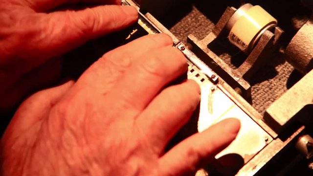 Film technician joins two 35mm film strips together with a film splicer