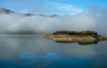 Symmetry island and mist reflected in water.