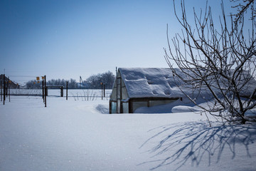 Greenhouse in snowdrift lit by moonlight at night