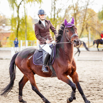 Young jockey girl riding horse on competition