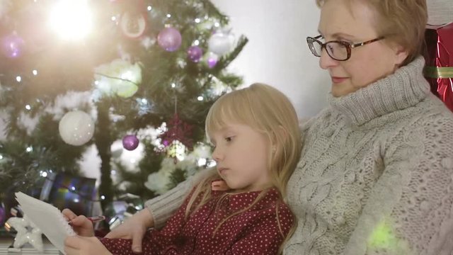 Grandmother with granddaughter write a letter to Santa.