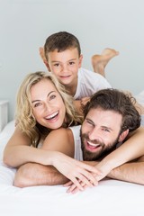 Portrait of parents and son lying on bed in bedroom