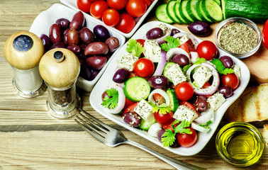 Greek salad with fresh organic vegetables,feta cheese ,herbs and olive oil on wooden background. Top view.Clean food concept.