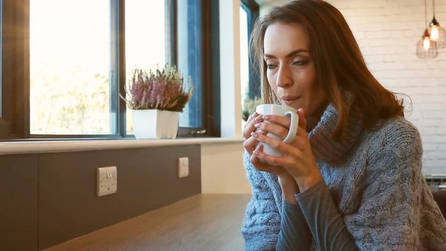 Beautiful young woman enjoying a hot drink in a coffee shop while relaxing and thinking