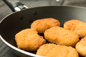 Cooked chicken nuggets in black frying-pan