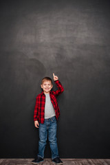 Happy boy standing over chalkboard and pointing up