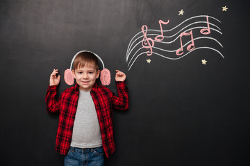 Kid listening to music over black chalk board with drawings