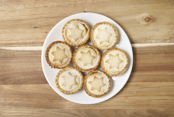Aerial view of a plate full of freshly baked mince pies on a wooden kitchen counter background