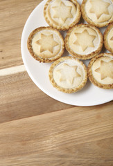 A plate full of freshly baked mince pies on a wooden kitchen counter background with blank space below