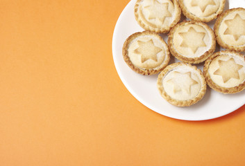 A plate full of freshly baked pies on a bright orange background with a blank space at side