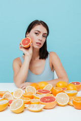 Beautiful young woman sitting and holding half of grapefruit