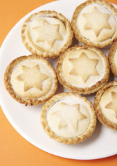A close up of a plate full of freshly baked fruit pies on a bright orange background