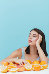 Woman with eyes closed sitting at table full of oranges