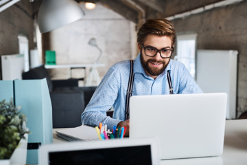 Young hipster, designer working on laptop at creative agency office