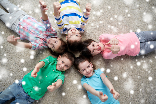 happy kids lying on floor and showing thumbs up