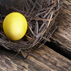 Colorful easter eggs in a nest on wooden background