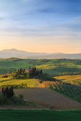 Farmhouse, green hills,cypress trees in Tuscany at sunrise in Italy - 128464026