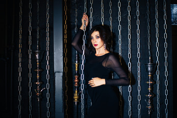 beautiful girl in a black dress on background of chains