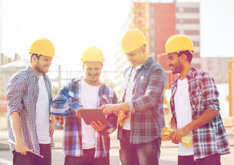 group of smiling builders with tablet pc outdoors